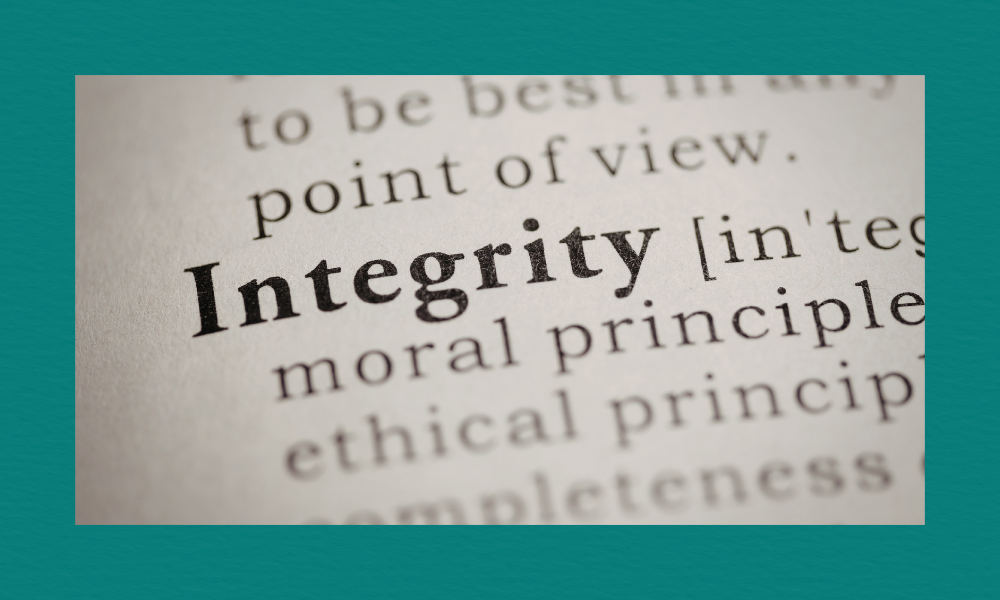 A close-up of a dictionary page showing the word “Integrity” in bold, with its phonetic spelling and part of its definition visible.