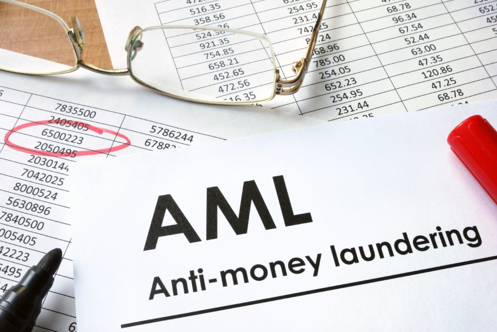 Anti-money lanudering typewritten on paper on desk with spreadsheets glasses pens amount circled in red