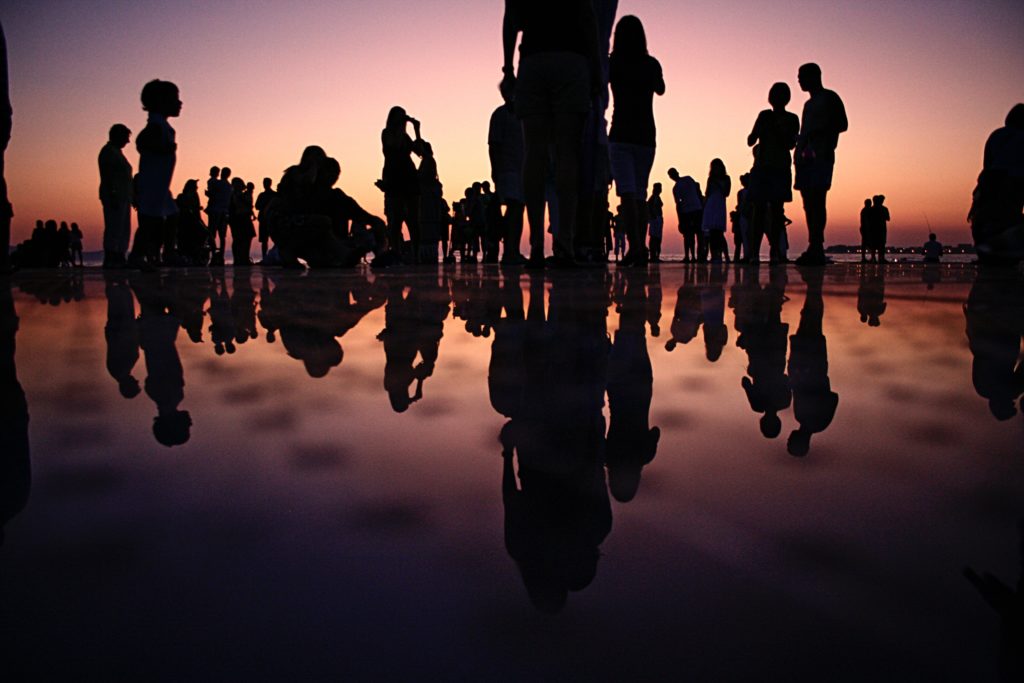 silhoutted group of people in perspective against dusk sky