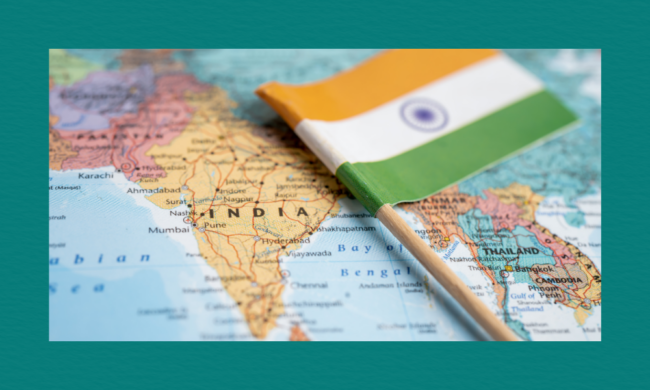A close-up map of South Asia with a small Indian flag pinned on India, showing surrounding countries and major Indian cities such as Mumbai, Pune, Hyderabad, and Ahmedabad.