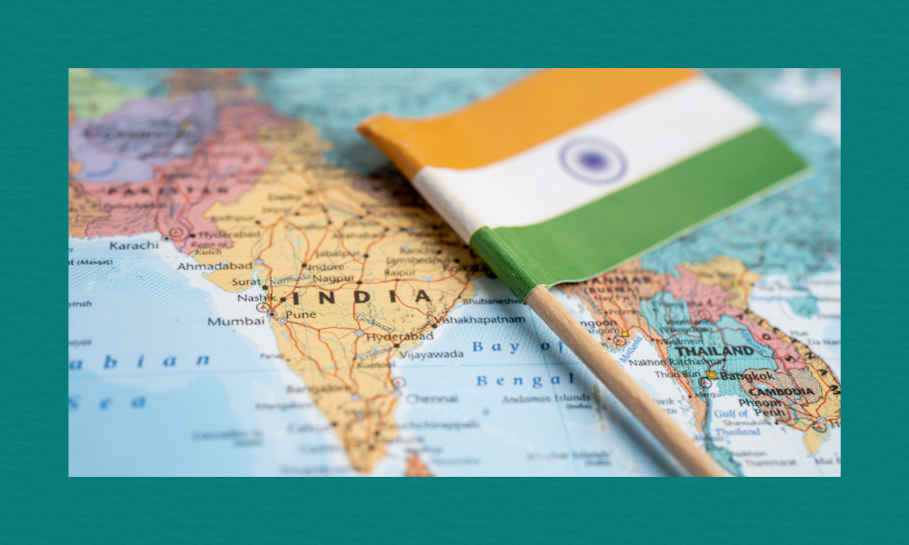 A close-up map of South Asia with a small Indian flag pinned on India, showing surrounding countries and major Indian cities such as Mumbai, Pune, Hyderabad, and Ahmedabad.