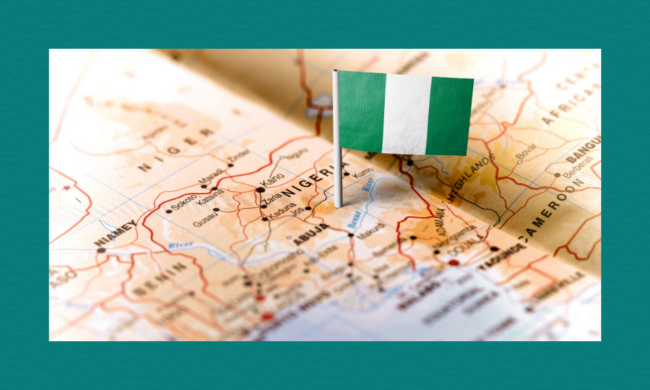 A close-up map of Nigeria with a small Nigerian flag pinned near Abuja, showing surrounding cities, borders, and neighbouring countries including Niger, Benin, and Cameroon.