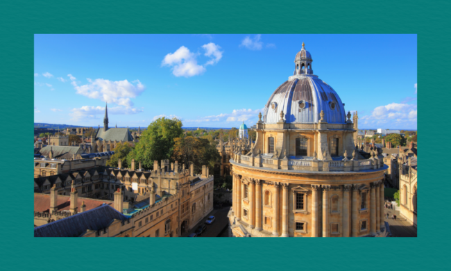 Aerial view of the Radcliffe Camera in Oxford, showing its circular stone structure and domed roof surrounded by historic university buildings with spires and ornate façades under a bright blue sky with scattered clouds.