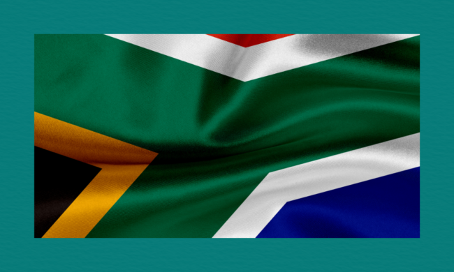 South Africa’s national flag with its green Y‑shape, black triangle bordered in yellow, and red, blue, and white sections, shown with a fabric texture and gentle folds.
