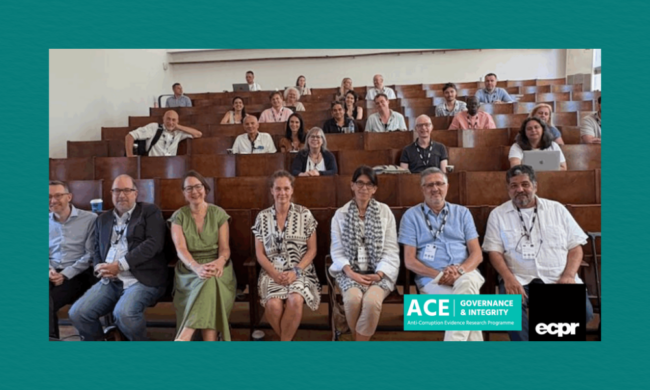 A lecture hall filled with attendees seated on tiered wooden benches, many wearing lanyards and name badges, listening attentively during an academic conference. Two logos—ACE Governance & Integrity Anti‑Corruption Evidence and ECPR—appear in the lower right corner.
