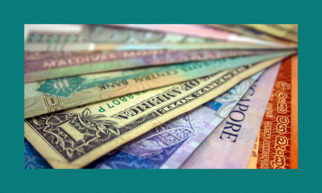Close-up of assorted international banknotes from multiple countries arranged in a fan-like spread, showing varied colours, designs, and denominations.