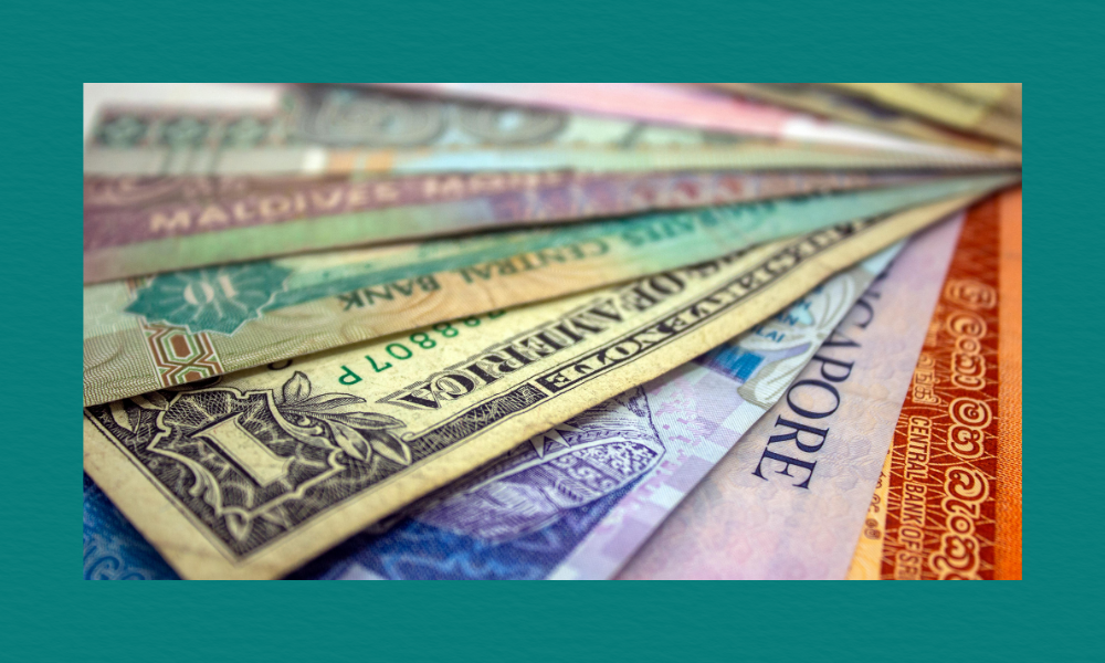 Close-up of assorted international banknotes from multiple countries arranged in a fan-like spread, showing varied colours, designs, and denominations.