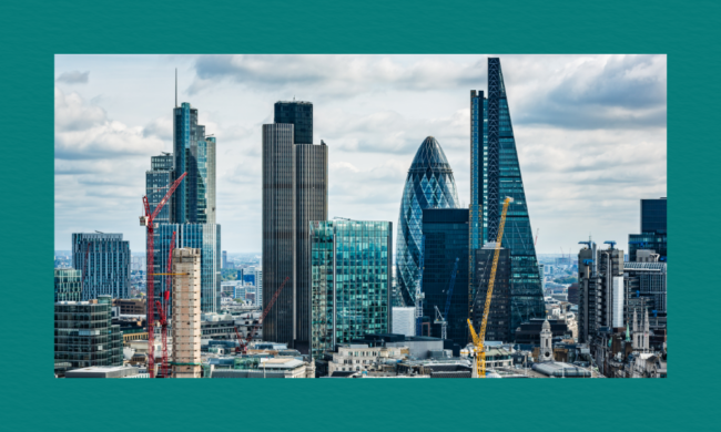 A view of London’s skyline featuring the Gherkin, the Cheesegrater, and other modern skyscrapers, with several construction cranes visible among the buildings. Older stone architecture sits in the foreground beneath a partly cloudy sky.